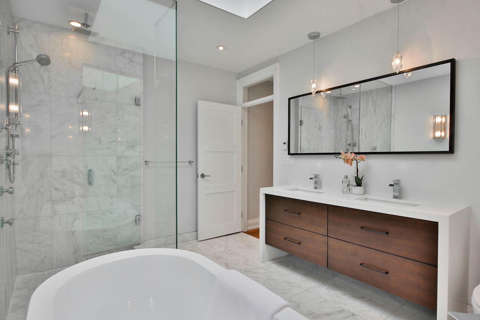 Remodelled bathroom with a frameless glass walk-in shower, freestanding tub and wood double vanity
