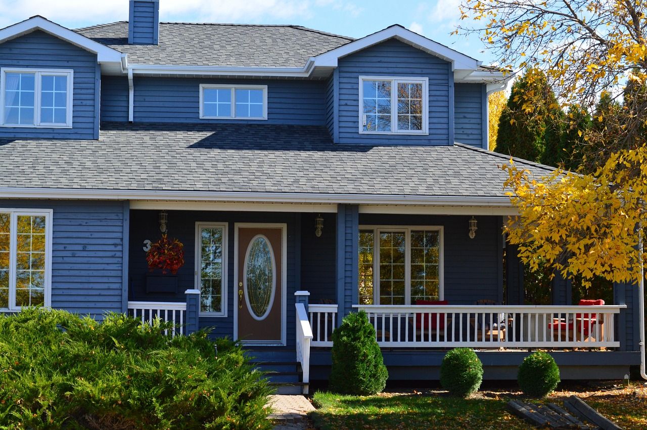 Two-story home with blue lap siding, a covered front porch and white gutters